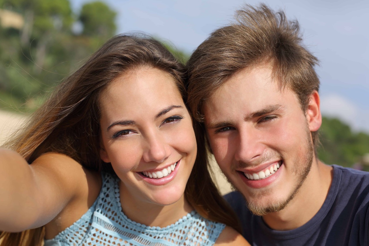 Smiling adult couple with straight teeth after orthodontic care by orthodontist in Mansfield, TX