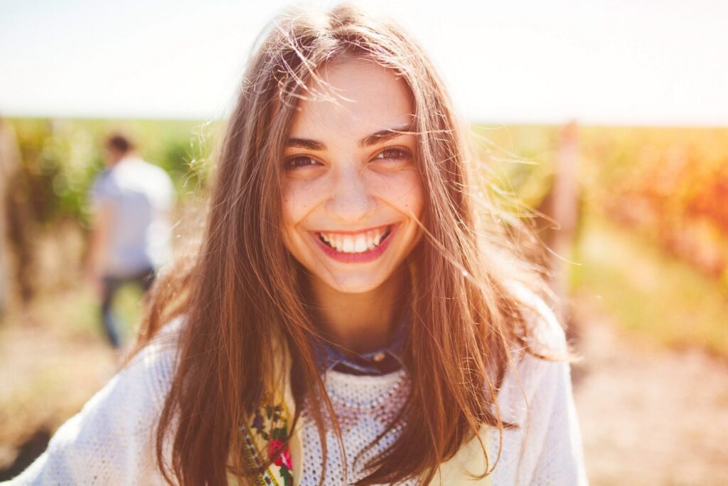 Smiling young woman outdoors in summer after orthodontic care from orthodontist in Mansfield, TX