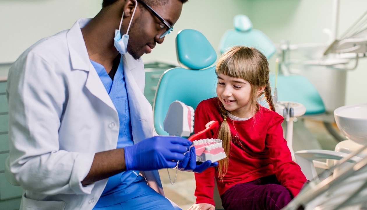 Orthodontist teaching young girl about dental care in Mansfield, TX